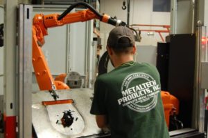 metaltech employee works on a robotic welding machine