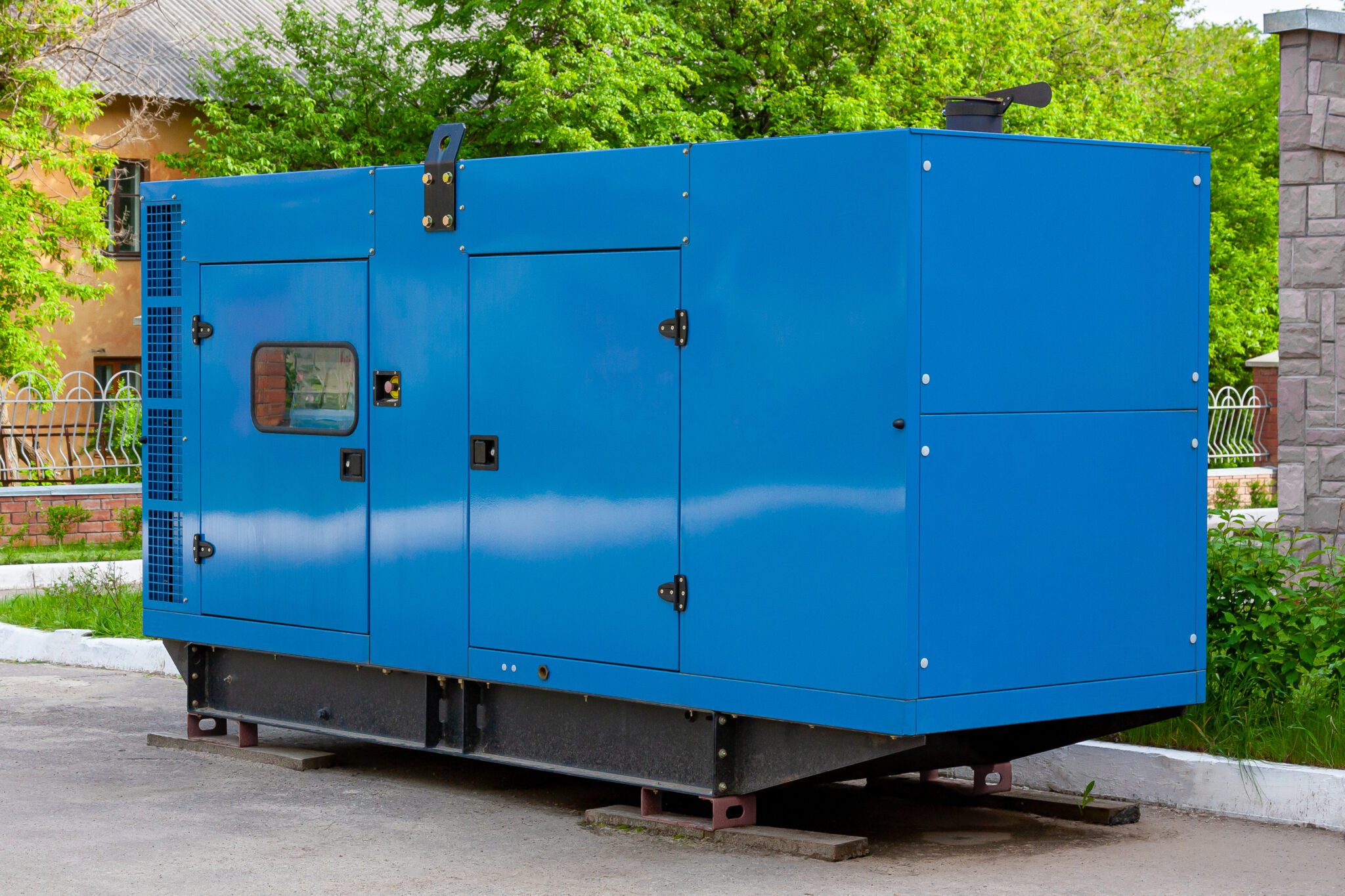 Diesel generator for emergency power supply at the wall of a medical center against the backdrop of green trees in fine weather. Close-up